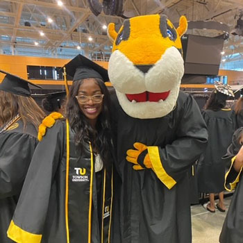 Emani Harris in a graduation gown and cap with a tiger mascot